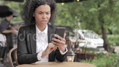 非洲妇女在智能手机上因<strong>失物招领</strong>，坐在室外咖啡厅
